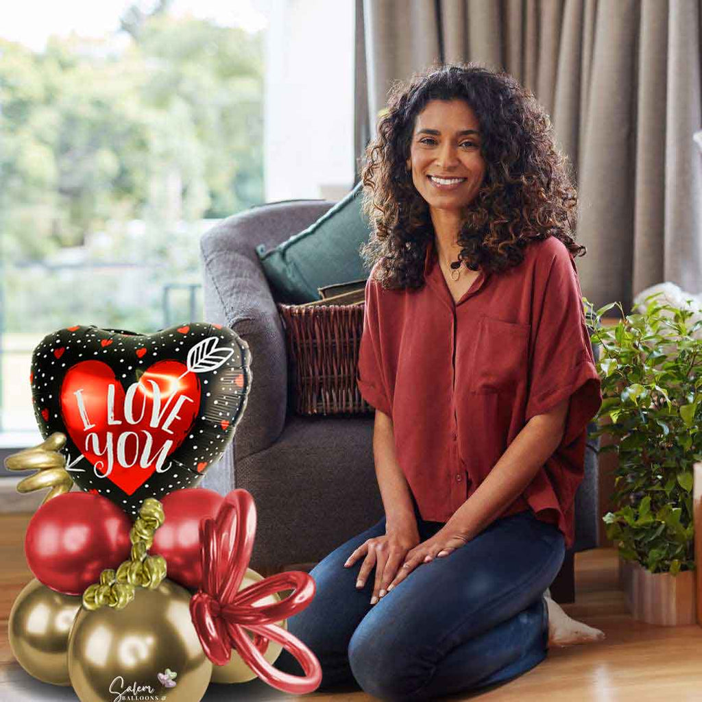 A young woman kneeling in front of Balloon bouquet featuring a heart-shaped balloon with an 