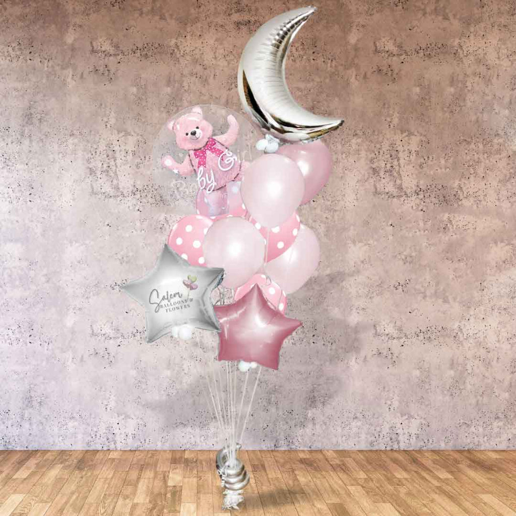 An It's a Girl Balloon bouquet in silver, pastel pink and white. Featuring a stuffed bubble balloon with a pink teddy bear, a large moon and stars standing in front of a cement wall
. Balloon delivery in Salem Oregon and nearby cities.