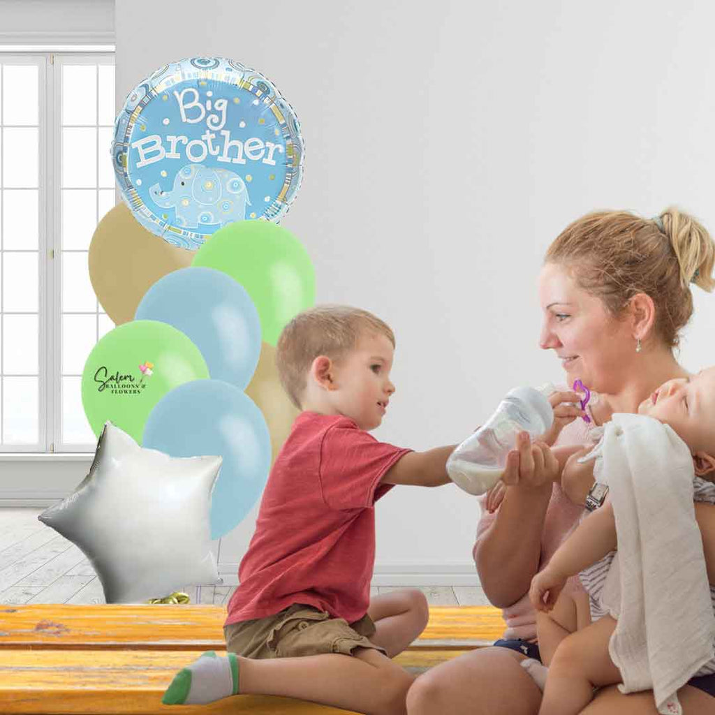 Mom holding a baby sitting next to the big brother and behind them a large balloon bouquet with a Big brother message. Salem Oregon balloon delivery.