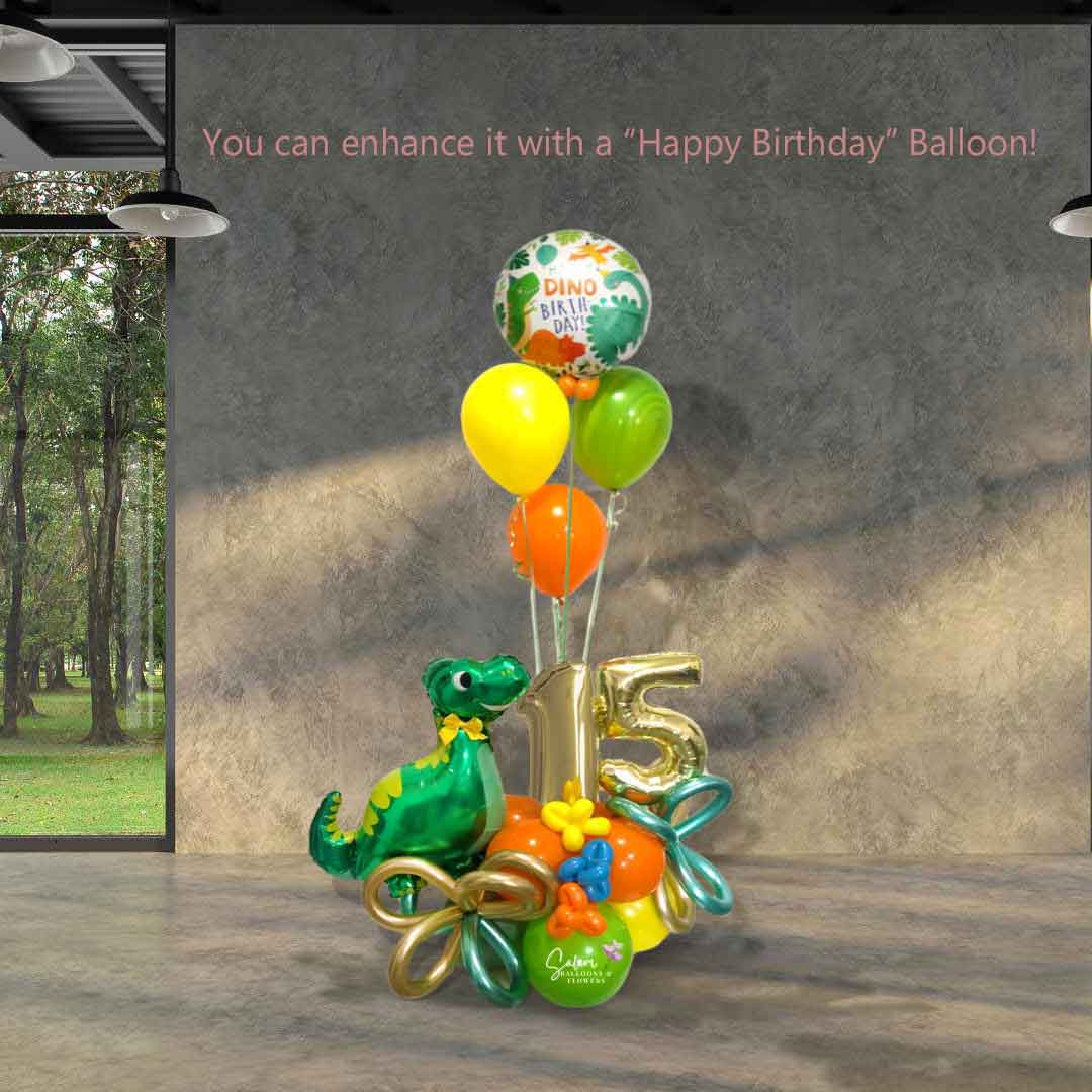 Dinosaur themed number balloon bouquet with a cute dinosaur balloon, in a kiwi green, orange and yellow color palette standing in front of a cement wall. Salem Oregon balloon delivery.