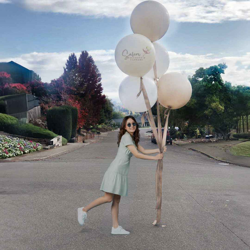 A young girl holding jumbo balloons  in beige, crean and white. Oregon Balloon decor.