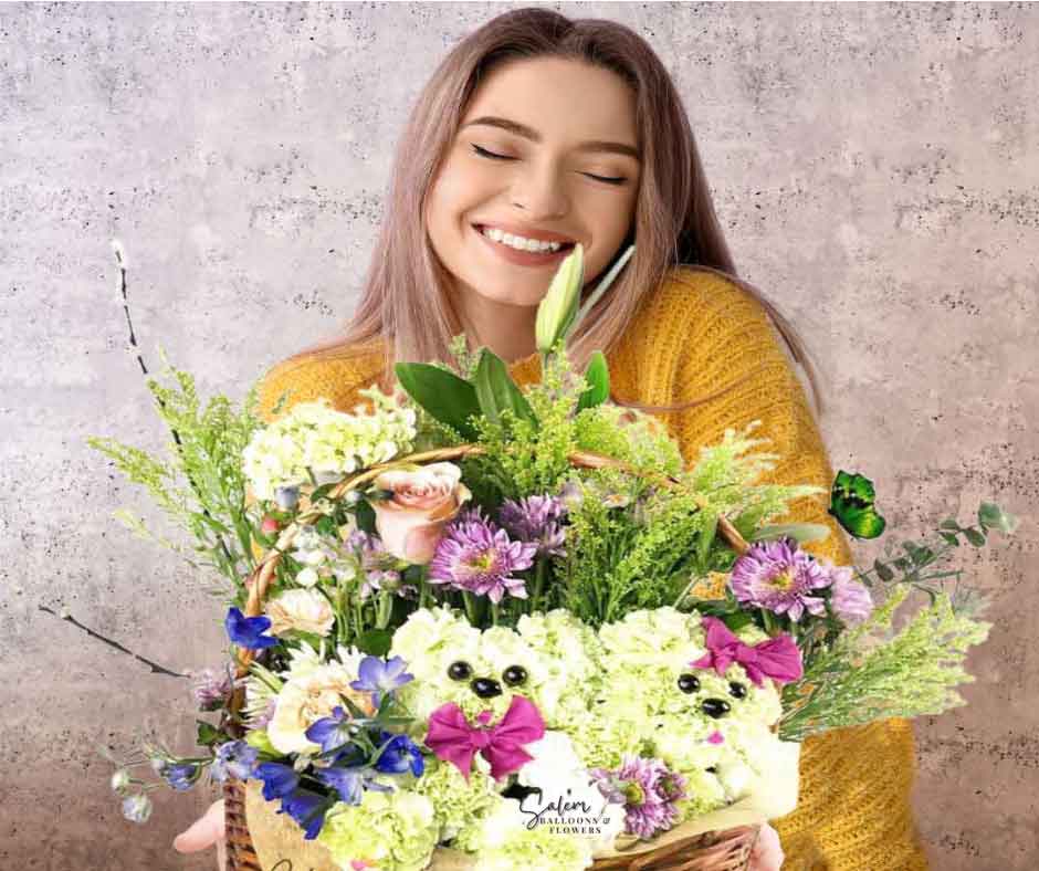 A young girl holding a wicker basket with 2 carnation flower puppies poking through flowers. Salem Oregon Flower delivery.