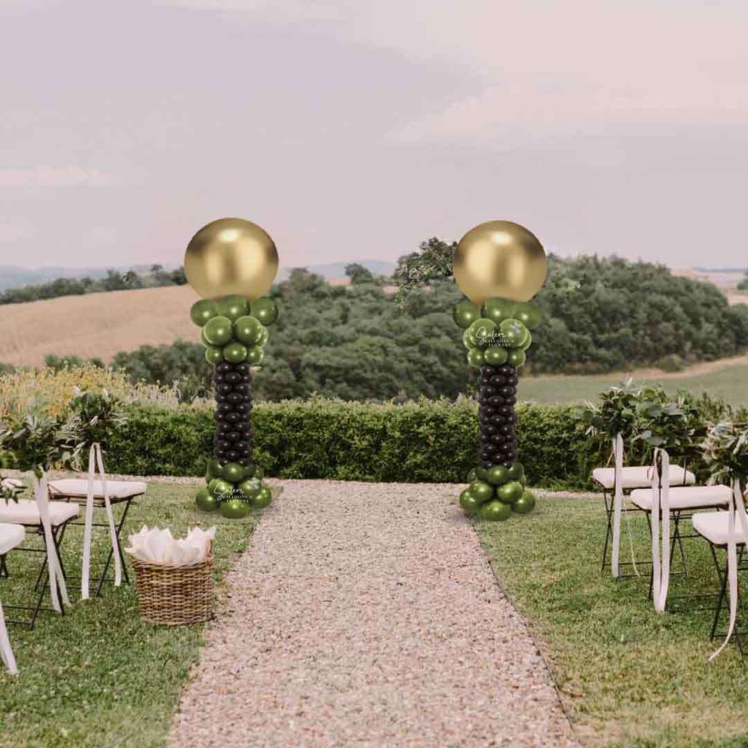 2 Balloon columns with a curvy form and round topper in gold and brown framing a wedding ceremony in a yard. Oregon Balloon Decor