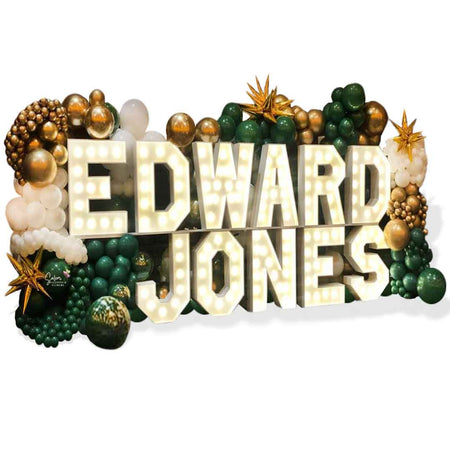 Light-Up marquee letters display spelling Edward Jones, nested in a 10 ft tall organic balloon wall in gold, green, and white. Salem Oregon Balloon Decor.