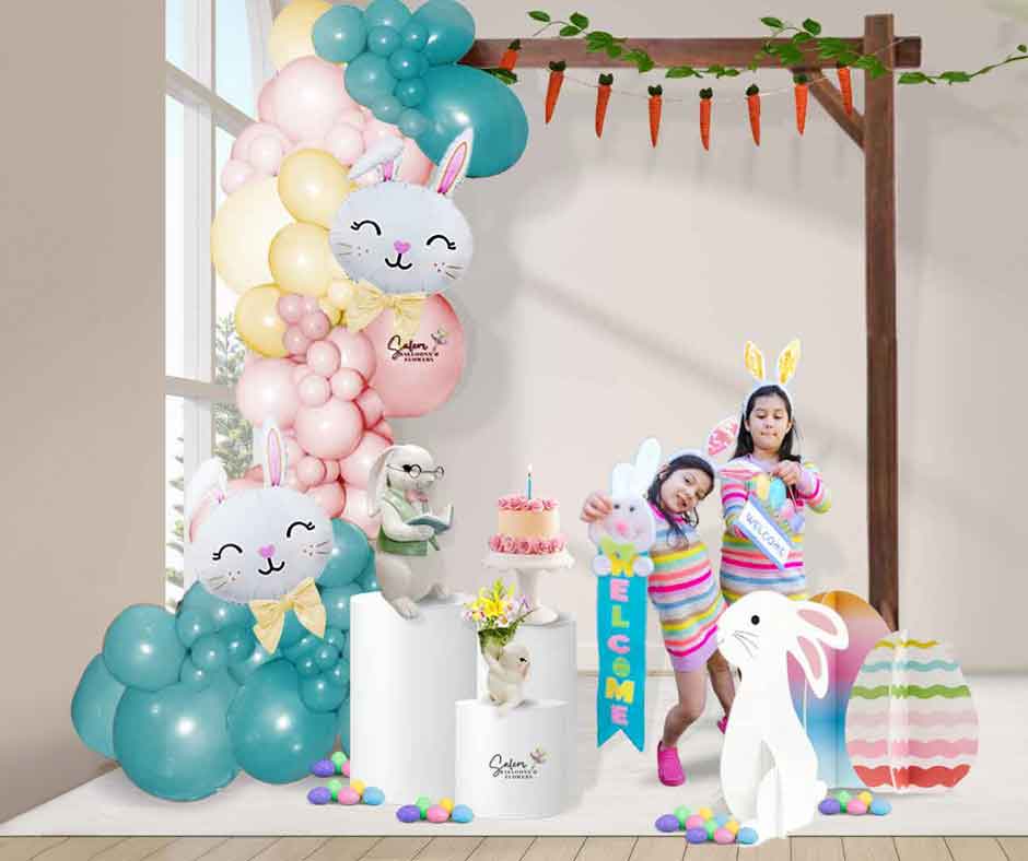 two girls posing at a Easter-themed organic balloon garland in pastel colors fixed to a wooden frame and decorated with bunny props, flowers and easter eggs. Salem Oregon balloon decor