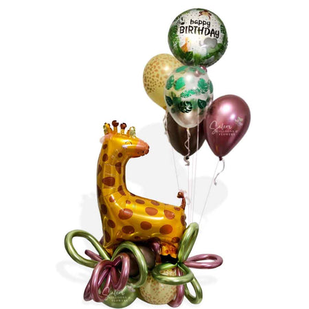 Safari themed balloon bouquet featuring a large Giraffe balloon standing on a balloon base with palm leaves and balloon bows and a set of helium balloons. Balloons Salem Oregon