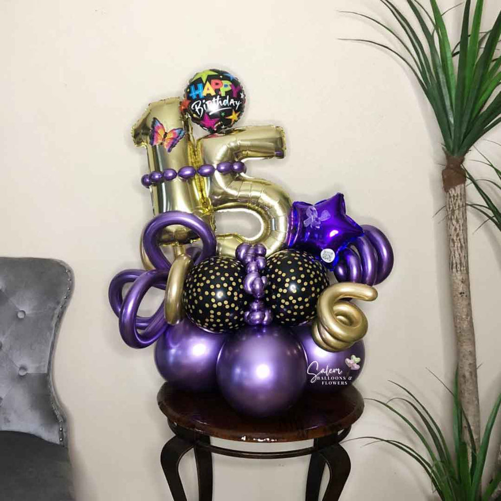 A gorgeous Number balloon bouquet. In purple and gold. Featuring 2 number balloons, curly balloons and a Happy Birthday message balloon, standing on a center table. Balloon delivery Salem Oregon and nearby cities.