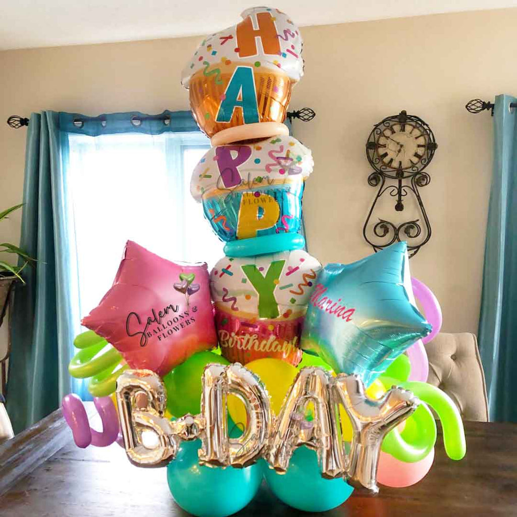 Birthday Balloon arrangement, featuring a tall stacked cupcakes balloon in vibrant colors. With a Happy Birthday message. Oregon Balloon Delivery.