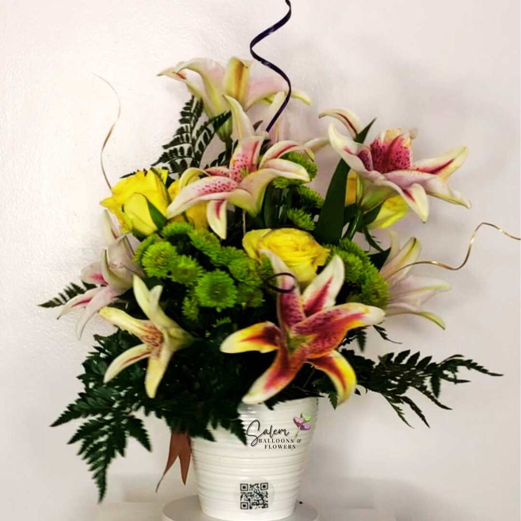 Flower arrangement with pink lilies, yellow roses and green moms in a white ceramic vase. Salem Oregon Flower delivery.