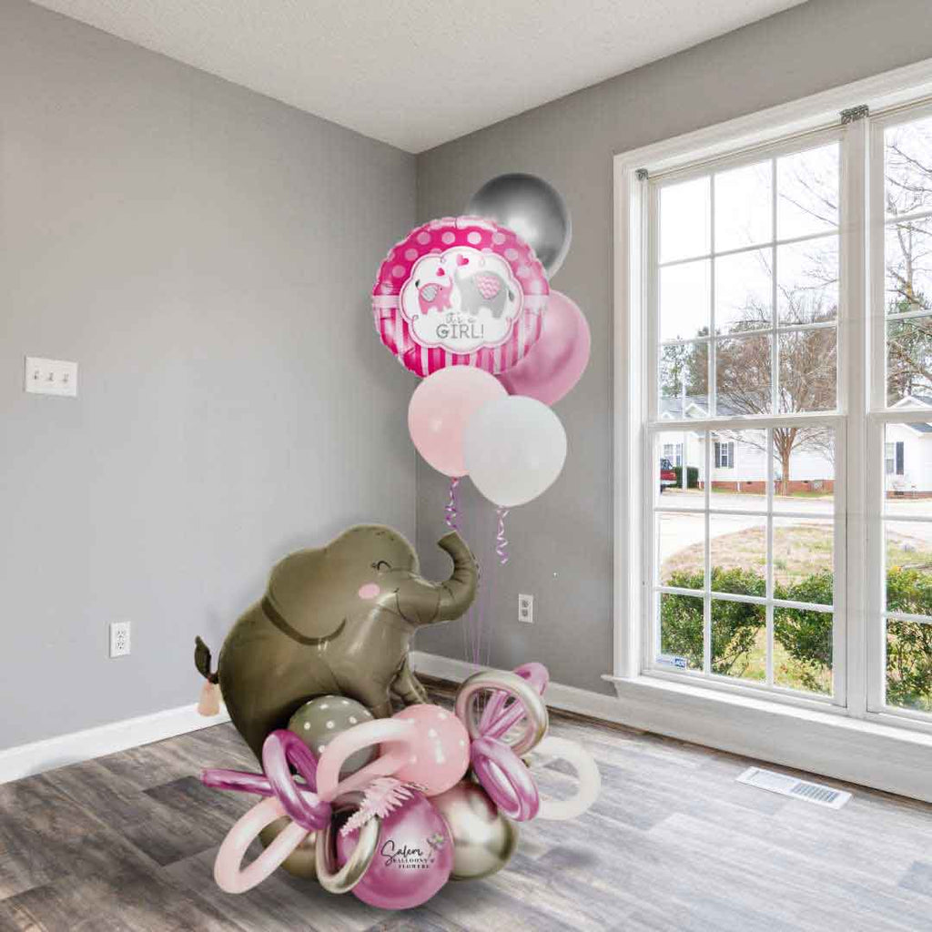 A Elephant themed balloon bouquet in a Pink and Gray color palette. Featuring a large elephant balloon holding a helium-filled balloon bouquet with a 