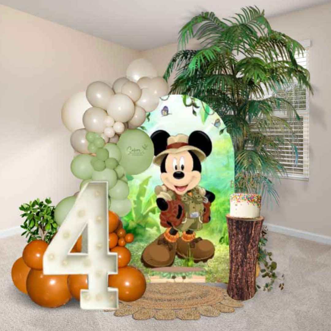 Mickey Mouse themed balloon decoration with balloon garland, cake stand and light up marquee number, decorated with 8 ft palm, round jute rug, and greenery. Oregon balloon decor