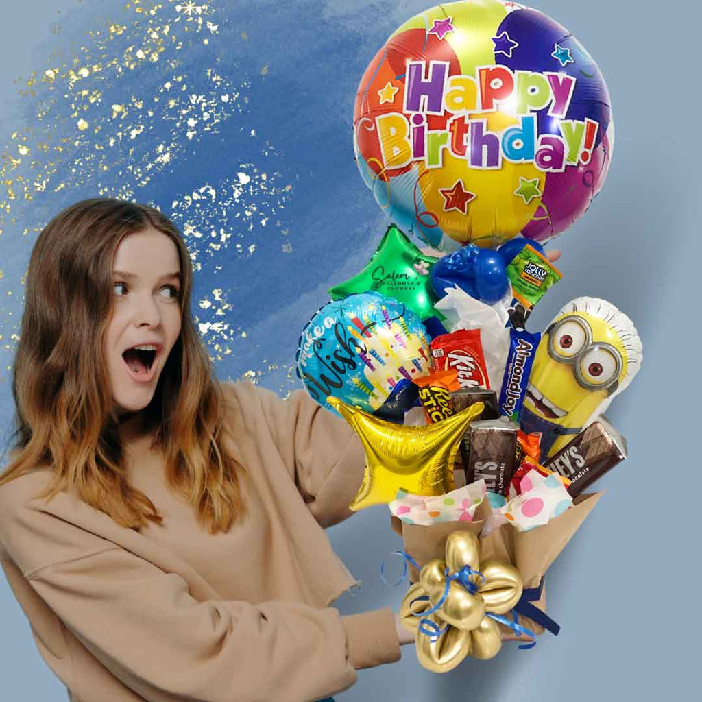 A girl holding a Minion-themed candy-balloon box. With a Mini Minion Mylar balloon holding a 