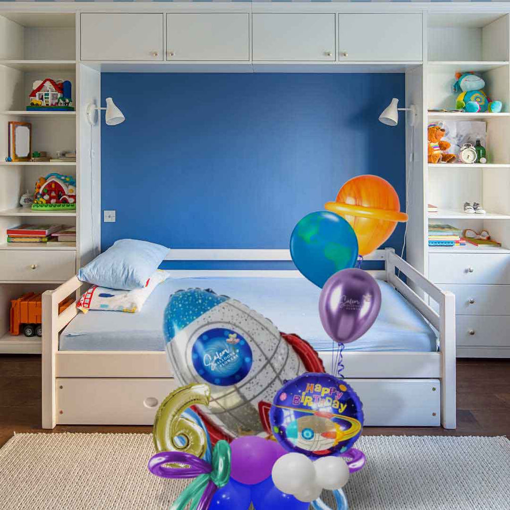 A Rocket themed balloon bouquet. with gold number balloon in blue, red, purple and gold color palette standing in front of a child's bedroom. Oregon Balloon Delivery.