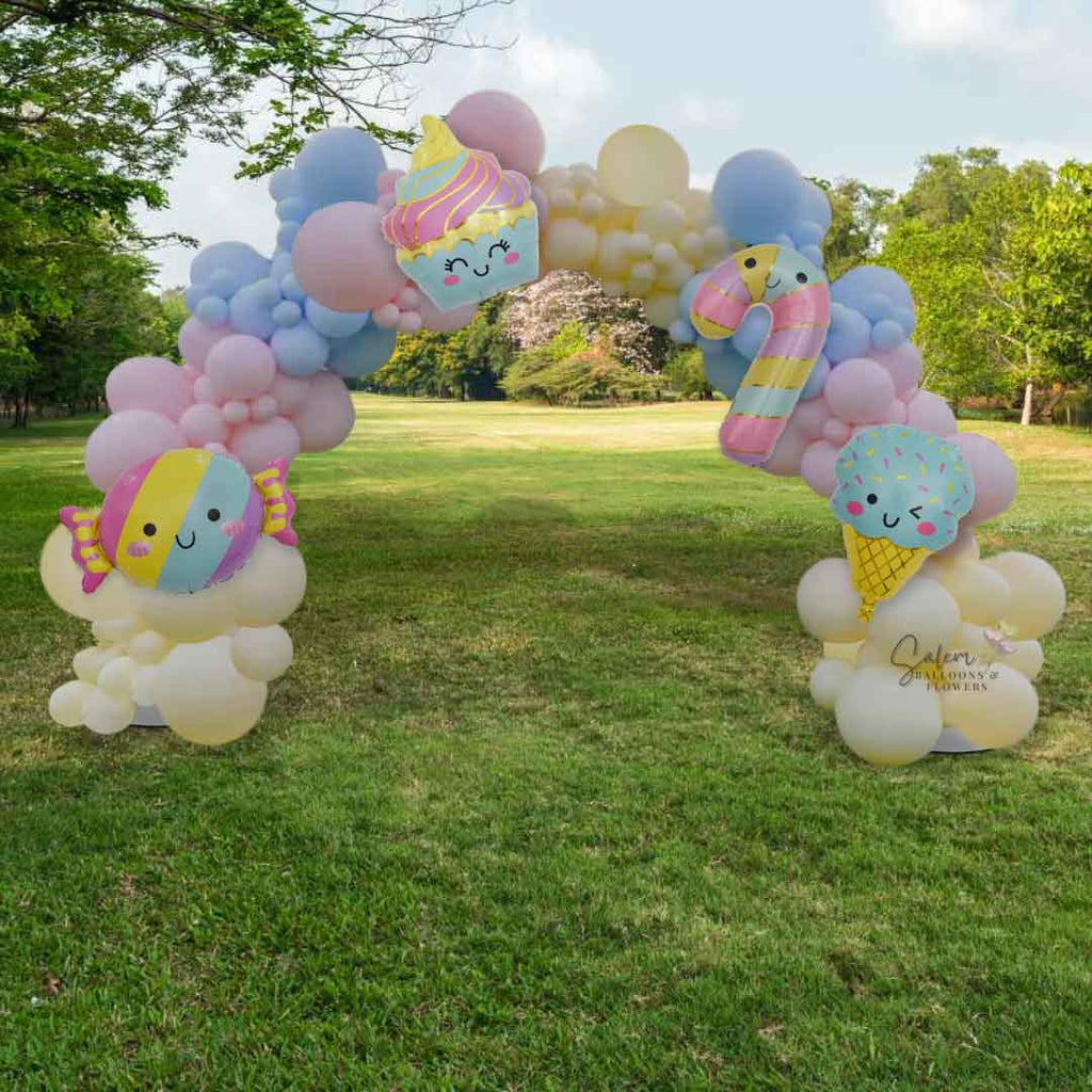 An organic balloon arch in pastel colors in a green grass open field. Oregon Balloon Decor.