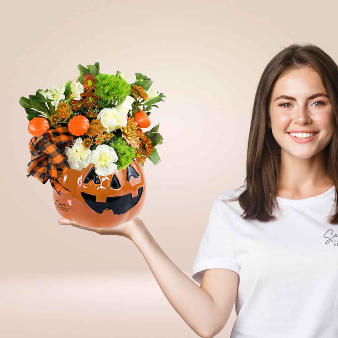 a young girl holding Fall flowers in a ceramic pumpkin head vase. Flower delivery Salem Oregon