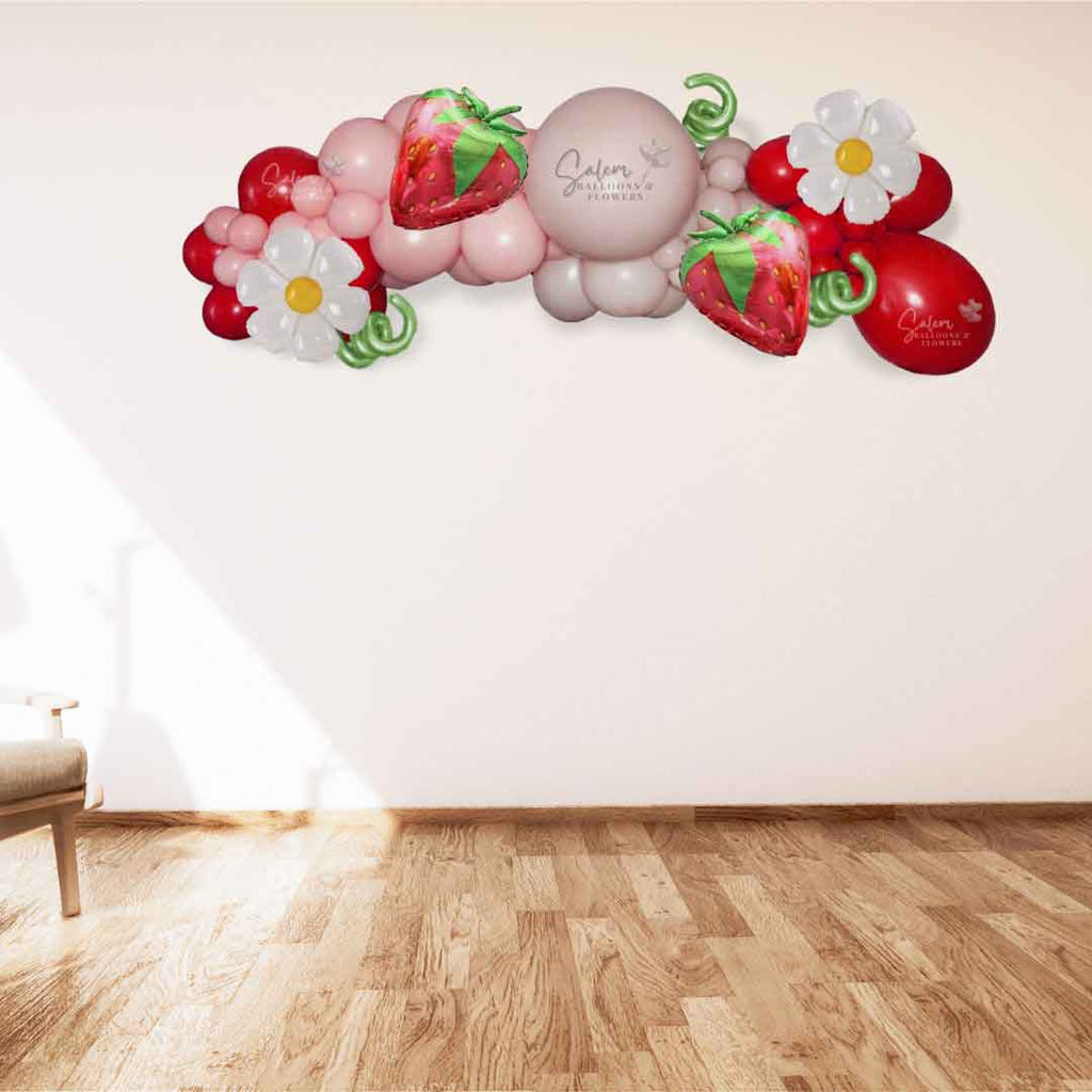 Strawberry Shortcake themed balloon decoration, featuring a balloon garland, in shades of in pinks, red and a touch of green. Balloon Decor. Oregon.