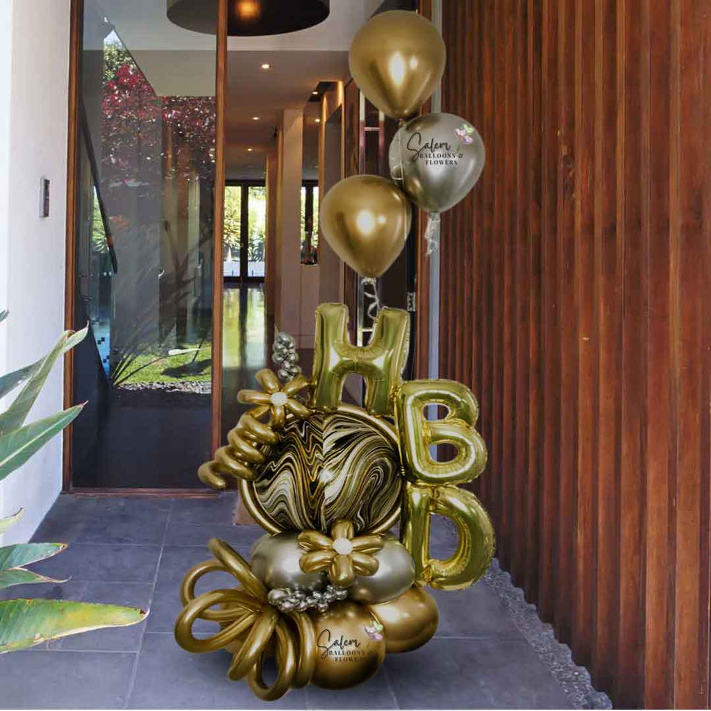 HBD Balloon bouquet. Luxury Balloon Arrangement. Featuring golden HBD letters, a marbled orbz balloon in gold, silver and black colors and decorated with golden flowers,curly balloons and a set of helium balloons in silver and gold. Oregon  Balloon Delivery.