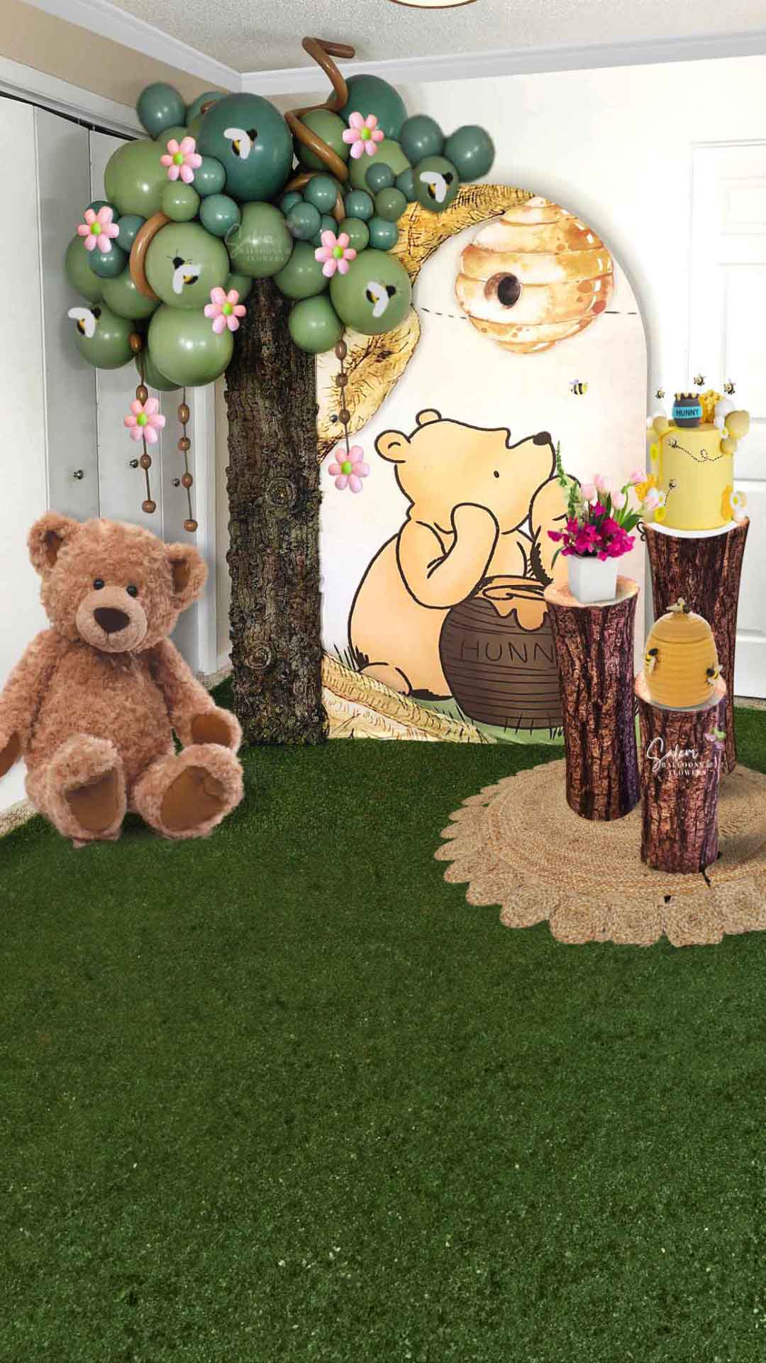 Winnie the Pooh themed balloon decoration, with balloon tree, Large teddy bear, cake stands with cake and flowers, and backdrop in a yellow, green and light blue palette. Oregon Balloon Decor. 