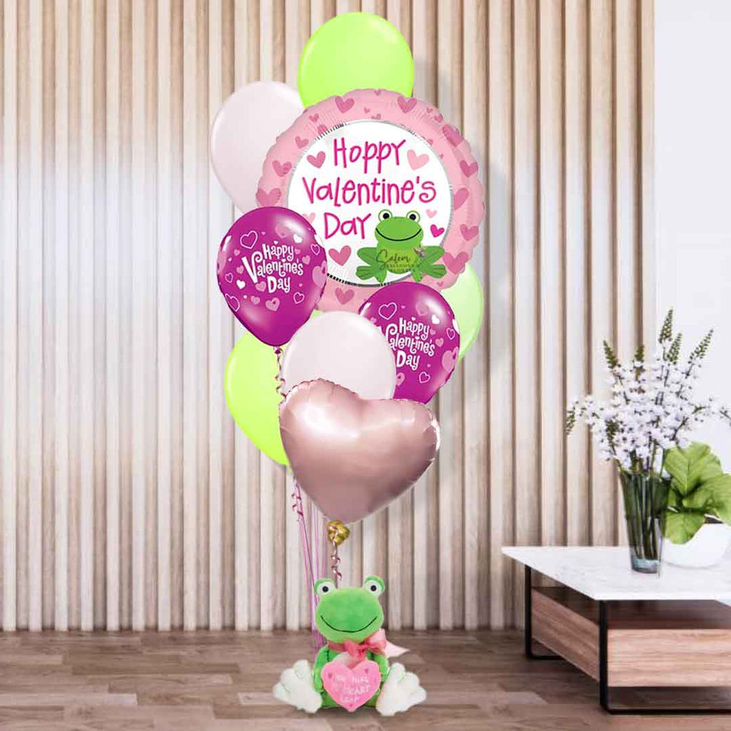 A sweet frog plush delicately holds a charming balloon bouquet and a heart that expresses your love with an embroidered 