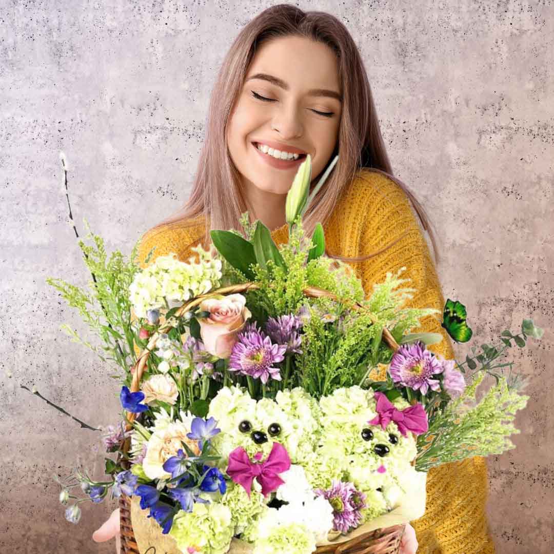 A young girl holding a wicker basket filled with 2 carnation flower puppies poking through flowers. Salem Oregon flower delivery